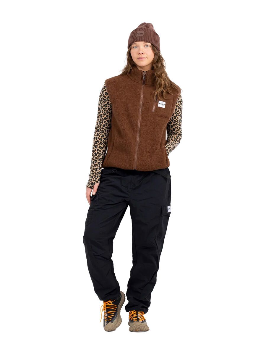 Eivy Fitted Outdoorhose in Schwarz kombiniert mit brauner Fleeceweste und gemustertem Langarmshirt.