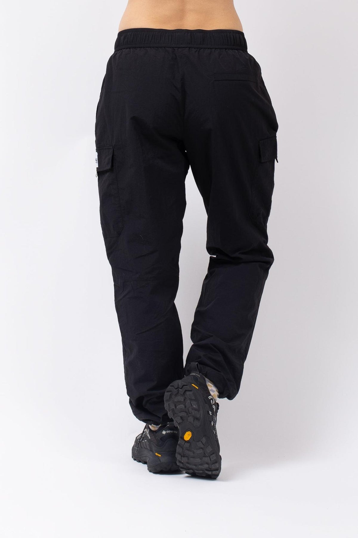 Rückansicht der schwarzen Eivy Fitted Outdoorhose mit elastischem Bund und seitlichen Beintaschen auf weißem Hintergrund.